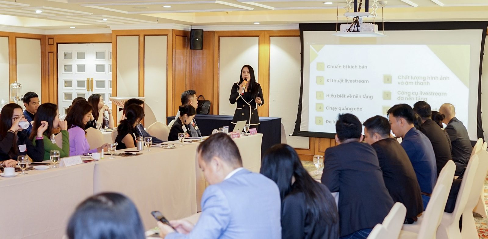 Mỹ Huyền đứng chia sẻ trước các chủ doanh nghiệp trong phòng hội thảo